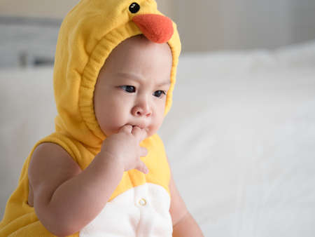 cute asian seven-month baby in white dress smiling with his mother in bedroom at homeの写真素材