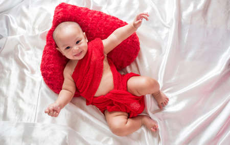 cute asian four-month baby in red dress smiling with heart. Happy valentine concept.