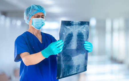 doctor wearing face mask inspecting the X-ray film of his medical patient in the room on hospitalの写真素材
