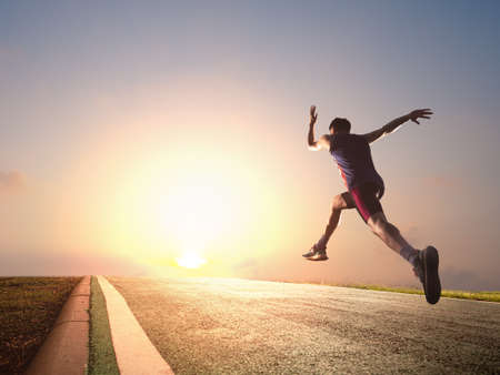 a man as athlete runner in high speed running action on the road toward the sunrise with bright sky backgroundの写真素材