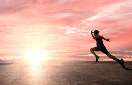 a man as athlete runner in high speed running action on the road toward the sunrise with bright sky...