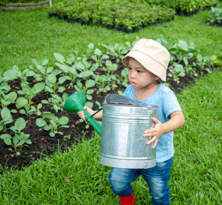 asian kid in a farmer dress growing some green sprout plants in the outdoor farm, a kid activity to learn the source of food.の写真素材