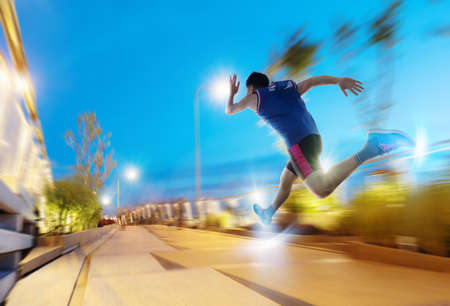 a man as athlete runner in high speed running action on the road toward the light with night sky backgroundの写真素材