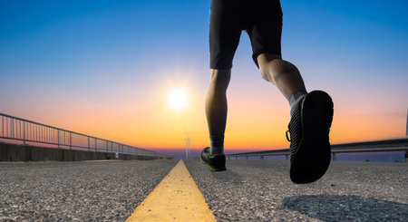a man as athlete runner in high speed running action on the road toward the sunrise with bright sky backgroundの写真素材
