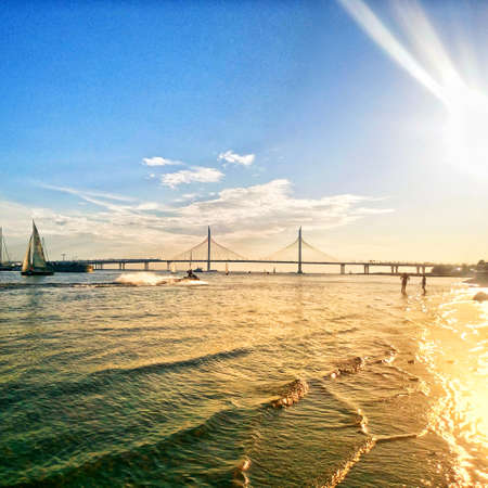 Beautiful sunset on a city beach, view to a boat and a bridgeの写真素材