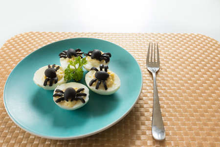 Appetizer for Halloween party: deviled eggs with black olives decorated as spider. On the blue...