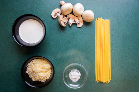 Ingredients for making mushroom pasta on dark green