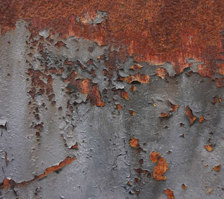 Grey paint peeling off metal container and revealing rusty surface. Close up shot.