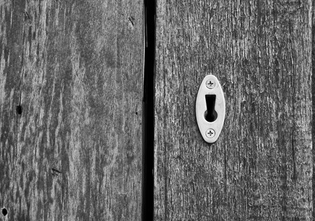 Close up picture of key hole on wooden door, in black and white tone.の写真素材