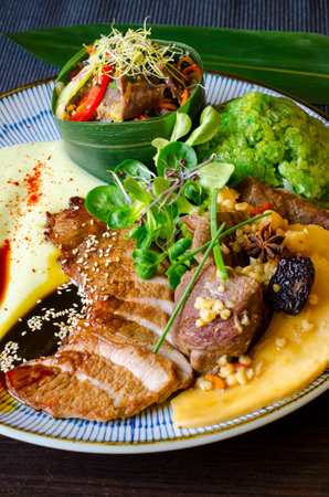 Grilled duck breast with rice, vegetables and sauce on a plateの写真素材