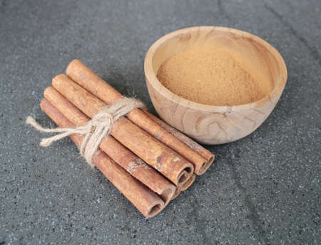 cinnamon stick and powder in wood bowlの写真素材
