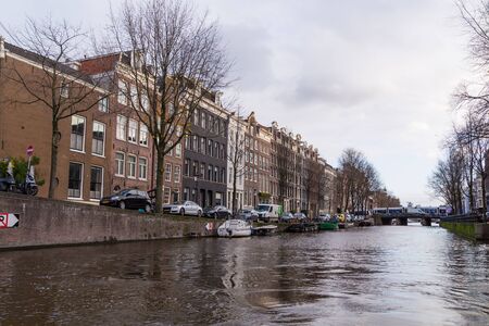 Amsterdam, Netherlands - November 28, 2019: View of Amstel river and typical buildings from tourist boat.のeditorial素材