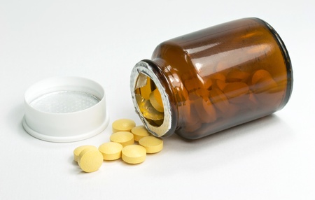 A bottle of scattered pharmaceutical pills lying on it s side