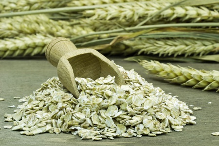 A small heap of oatmeal flakes with wooden scoop