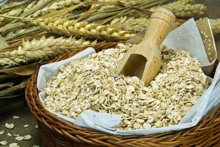 Oatmeal flakes in a basket with wooden scoop
