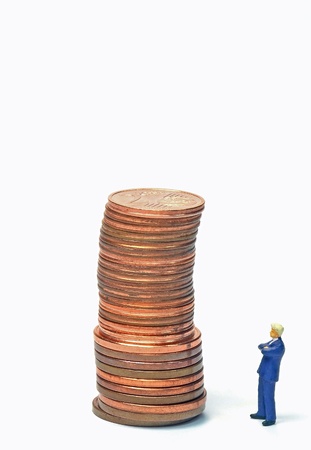 A miniature businessman looking at a pile of money の写真素材