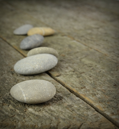 A row of pebbles lying on a wooden background with copy spaceの写真素材