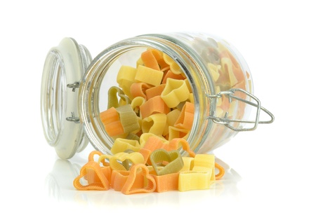 An open glass jar of pasta lying on a white backgroundの写真素材