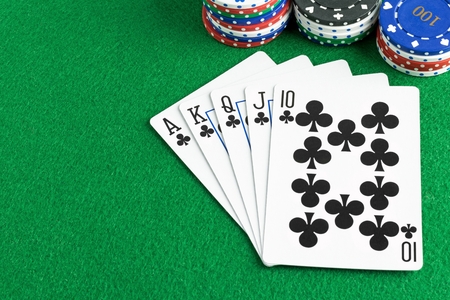 A royal flush poker hand with chips and green felt table copy space
