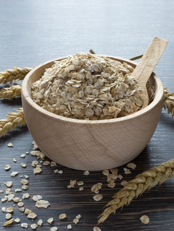 A bowl of oatmeal flakes on a wooden background