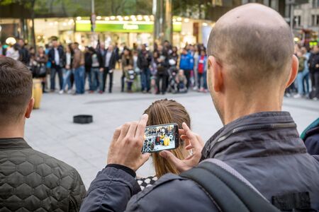 NIEDERSACHSEN, GERMANY SEPTEMBER 26, 2015: A GDPR data protection conceptual image of a man photographing and videoing street performers in public with a mobile smart phone.のeditorial素材