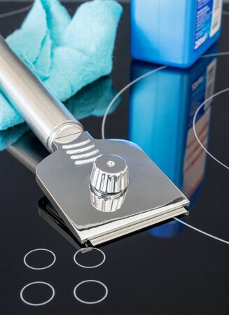 Cooker cleaning scraper and utensils on top of a shiny ceramic hobの写真素材