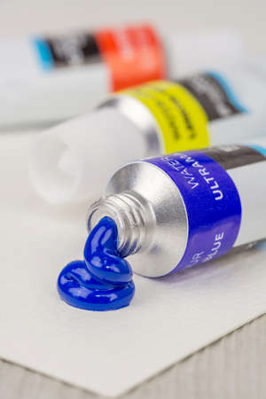 An open tube of blue watercolor paint with some squeezed out paint on paperの写真素材