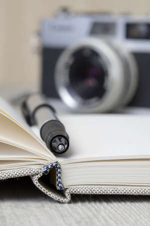 A travel log journal concept with an open book, pen and cameraの写真素材