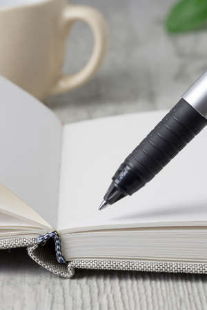A close up of a pen and an open journal diary notebook on a wooden tableの写真素材