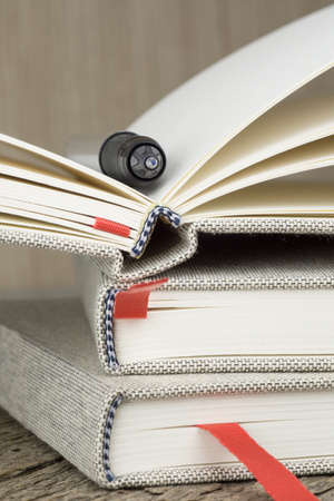 A pile of journal diary notebooks with a pen on a wooden tableの写真素材
