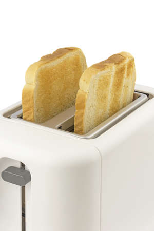 A close up of two slices of golden brown toast in an electrical toaster on a white backgroundの写真素材