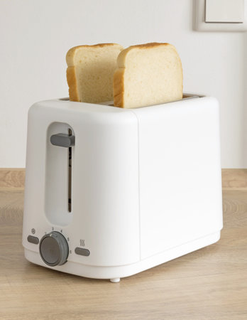 Two slices of white bread ready for toasting in an electrical toaster on a wooden kitchen worktop...