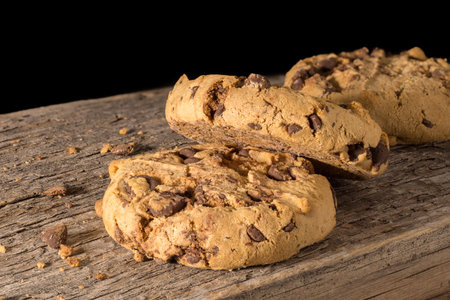 A group of chocolate chip cookie biscuits lying on a rustic wooden table
