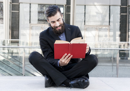 young hipster reading a book sitting outdoorsの写真素材