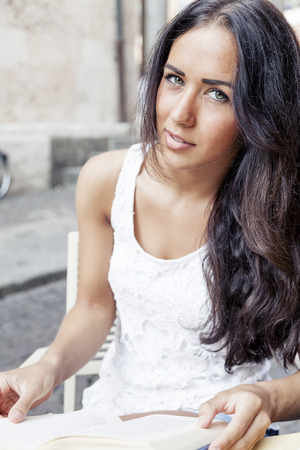 portrait of attractive girl while reading book in a coffee barの写真素材