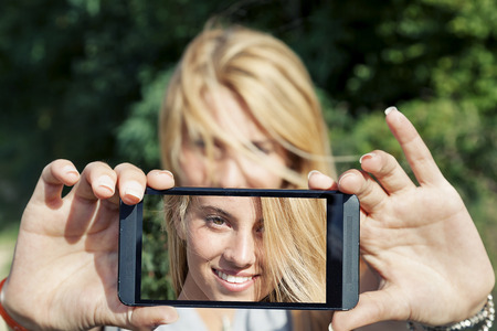 pretty woman with blond hair take a selfie with smart phoneの写真素材