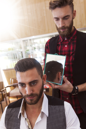 young hipster barber shows haircut to a customerの写真素材