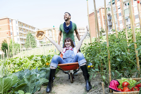 man pushes his girlfriend in wheelbarrow in the gardenの写真素材