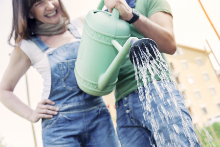 beautiful engaged couple watering plants in the gardenの写真素材
