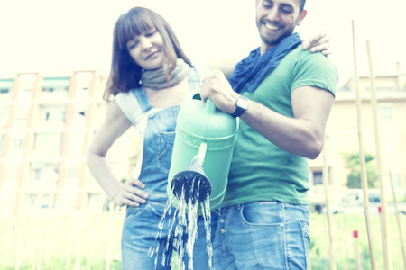 beautiful engaged couple watering plants in the gardenの写真素材