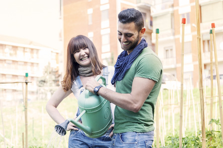 beautiful engaged couple watering plants in the gardenの写真素材
