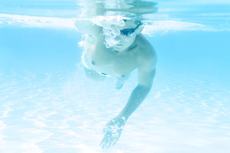 young man swimming the front crawl style in a poolの写真素材