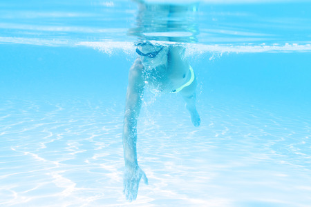 young man swimming the front crawl style in a poolの写真素材