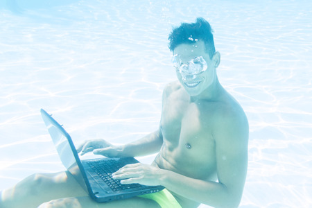 young man enjoying his laptop underwaterの写真素材