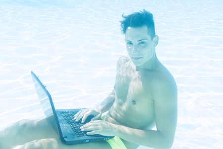 young man enjoying his laptop underwaterの写真素材