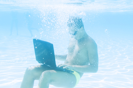 young man working with his laptop underwaterの写真素材