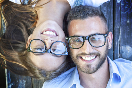 portrait of young couple lying on wooden benchの写真素材