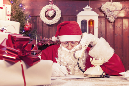 portrait of santa claus on the phone at his home compiles the wishlist for christmasの写真素材