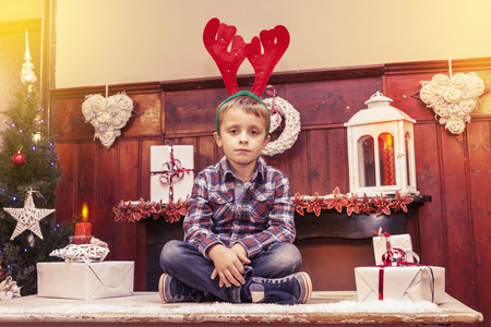 young boy waiting for santa claus sitting on the tableの写真素材