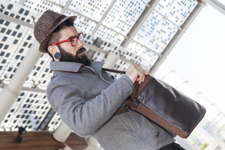 young hipster businessman looking in his shoulder bagの写真素材
